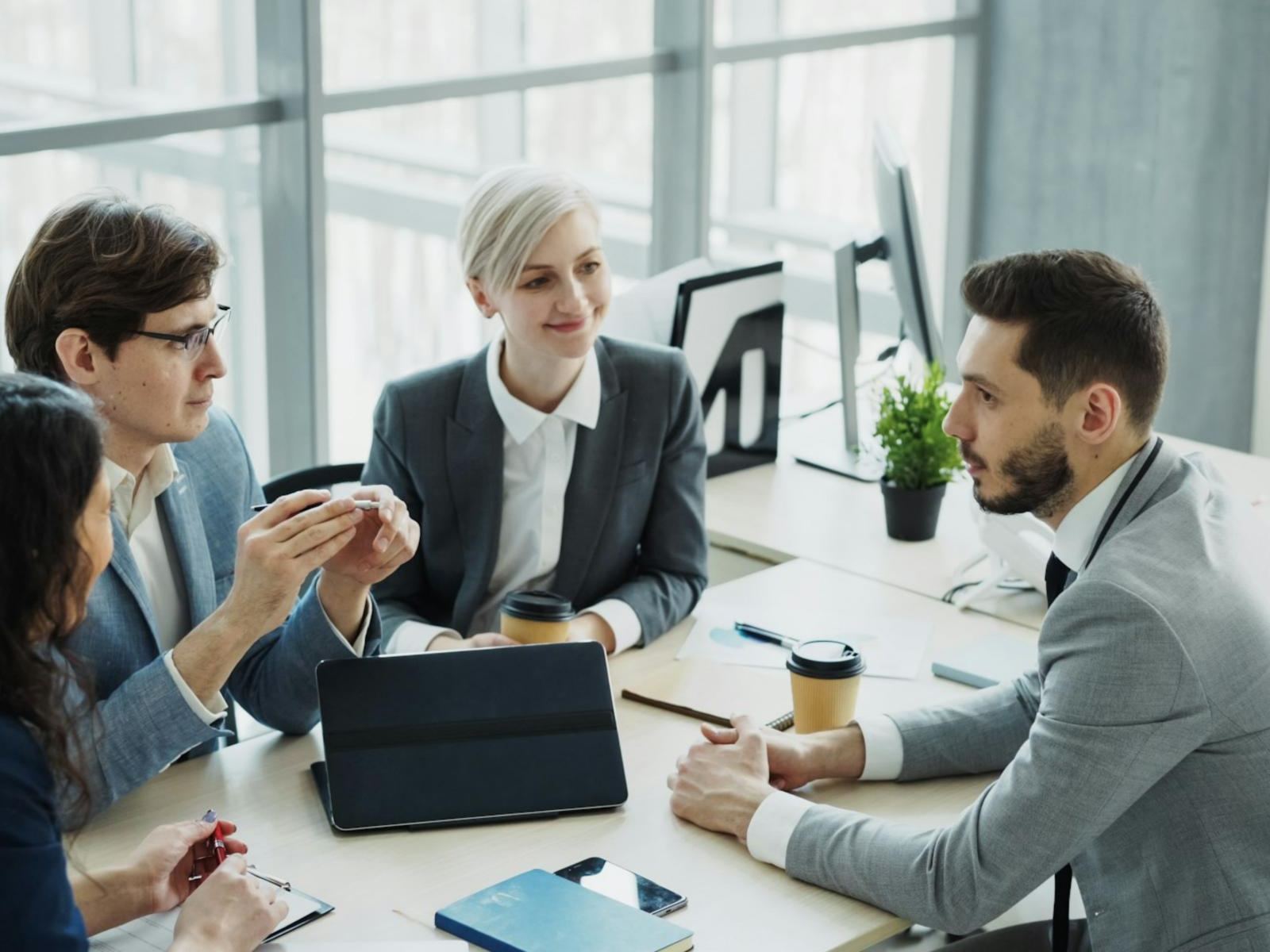 Colleagues discussing work around a table in a bright office